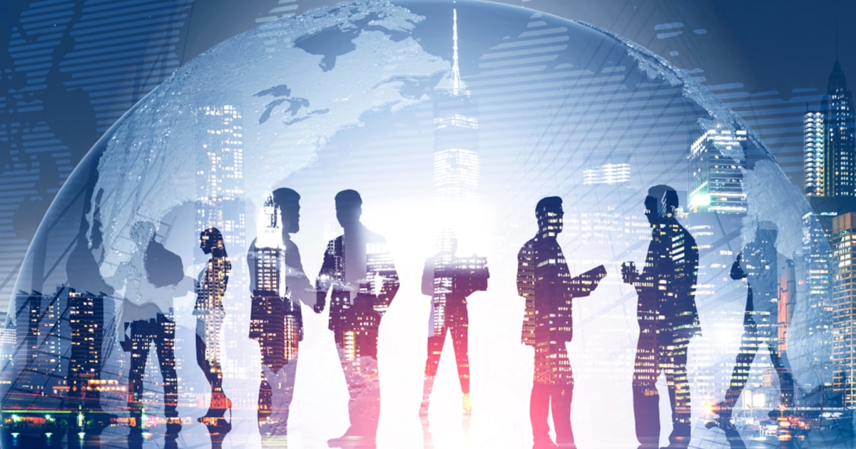 businessmen huddled together in front of world globe